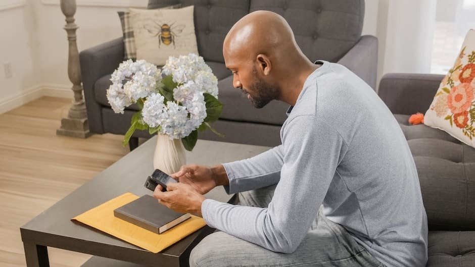 A Man Sitting on a Couch while Using His Smartphone