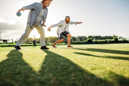 Senior men playing boules in a lawn